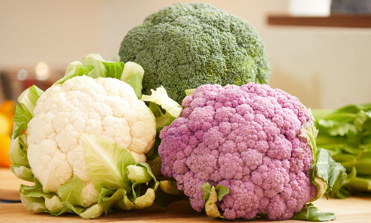 Green, white and purple cauliflower on a cutting board